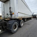 White refrigerated trailer beside the road.