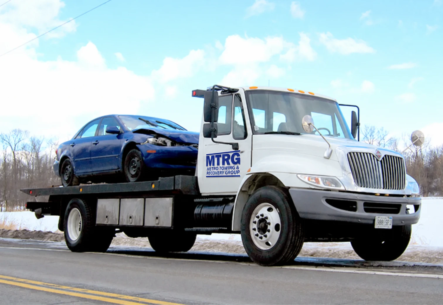 MTRG flatbed carrying a damaged blue car on a winter road